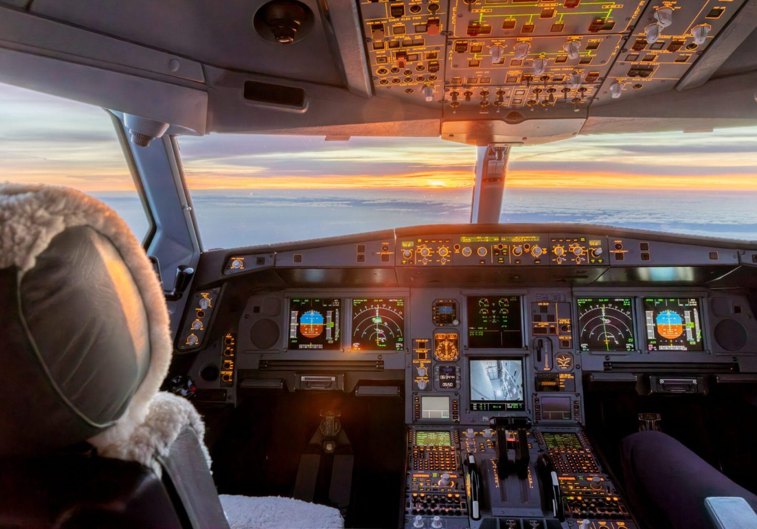 Airplane cockpit with sunset view outside.
